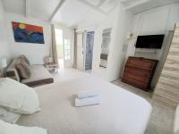 a white bedroom with a large bed and a television at La Rose du Bresil Marie-Galante in Capesterre