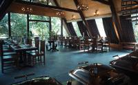 a dining room with tables and chairs and windows at LA SELVA Resort, Pench National Park in Khawāsa