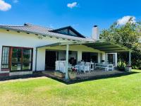 a house with a porch with white tables and chairs at Porterfield Guest House, Champagne Valley in Champagne Valley
