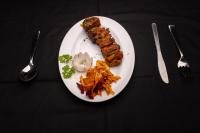 ein Teller mit Fleisch und Gemüse auf einem Tisch in der Unterkunft AATHAVAN MATICHI ECO RESORT in Panhāla