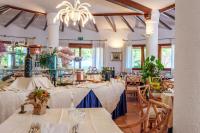 a restaurant with white tables and chairs and a chandelier at Hotel Punta Est in Baja Sardinia