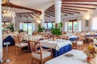 a restaurant with white tables and chairs and windows at Hotel Punta Est in Baja Sardinia