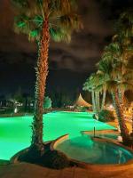 a swimming pool with palm trees at night at Bungalow de 3 chambres avec piscine partagee et terrasse a Vias a 1 km de la plage in Vias