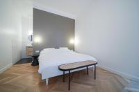a bedroom with a white bed and a bench at Parisuites Central Grands boulevards Design Folies Bergères in Paris