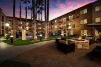 Un patio de hotel con fogata y palmeras. en Sonesta Select Huntington Beach Fountain Valley, en Huntington Beach