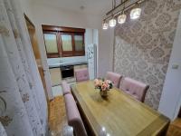 a dining room with a wooden table and pink chairs at Apartman Danijela in Vukovar