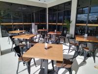 a cafeteria with wooden tables and chairs and windows at Acro Residences in Guiguinto