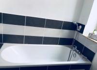 a bath tub in a bathroom with black and white tiles at Haussemannien in Nevers