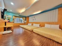 two beds in a room with wooden floors at Xing Ji Hotel in Kenting
