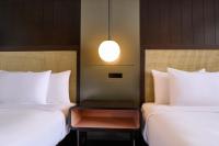 two beds in a room with a table between them at Hotel Renew in Honolulu
