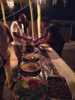 un grupo de hombres parados alrededor de una mesa con comida en Deep south Eco-lodge, en Marsa Alam