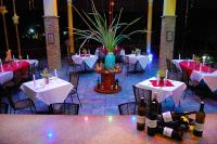 ein Restaurant mit weißen Tischen und Weinflaschen in der Unterkunft Crystal Paradise Resort Spa & Winery in Narra