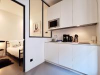 a kitchen with white cabinets and a bed in a room at Le PETIT BALCON by Booking Guys in Nice