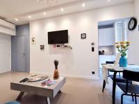 a living room with a table and a tv on a wall at Le PETIT BALCON by Booking Guys in Nice