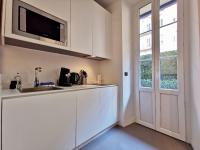 a kitchen with white cabinets and a tv on the wall at Le PETIT BALCON by Booking Guys in Nice
