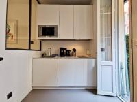 a kitchen with white cabinets and a microwave at Le PETIT BALCON by Booking Guys in Nice