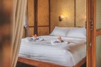 two dolls are sitting on a bed in a bedroom at Banyan Bay Villas in Ko Jum