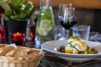 un tavolo con un piatto di cibo e un bicchiere di vino di La Chaumière Mountain Lodge a Chamonix-Mont-Blanc