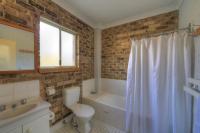a bathroom with a toilet and a tub and a sink at Acacia Snowy Motel in Jindabyne
