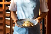 een chef-kok die een kom met eten in zijn handen houdt bij OUTRIGGER Surin Beach Resort in Surin Beach