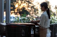 een vrouw aan een tafel met een glas wijn bij OUTRIGGER Surin Beach Resort in Surin Beach