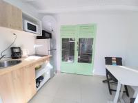a kitchen with a green door and a table at La Rose du Bresil Marie-Galante in Capesterre
