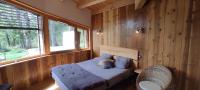 a bedroom with a bed in a wooden wall at Bulle de Bois, écolodge insolite avec spa privatif au milieu des volcans - Bulles d&#39;Herbe in Queyrières
