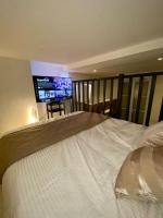 a bedroom with a large white bed with a television at Spacious LOFT near JARDIN du LUXEMBOURG in Paris