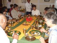 Un grupo de personas sentadas alrededor de una mesa comiendo comida en Mancotta Heritage Chang Bungalow, en Dibrugarh