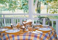 una mesa con platos y vasos encima en Mancotta Heritage Chang Bungalow, en Dibrugarh