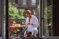 a woman in a robe sitting at a table on a balcony at Hôtel Toujours &amp; Spa in Paris