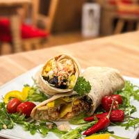 a burrito on a plate with vegetables on a table at Hotel Bergstätter Hof in Immenstadt im Allgäu