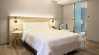 a bedroom with a large white bed and a chair at HINOEN Hotel in Taipei