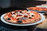 een pizza op een wit bord op een tafel bij Beekite Wind Village in Luis Correia