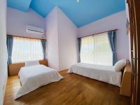 two beds in a room with blue ceilings and wooden floors at Kenting COMIC B&amp;B in Hengchun South Gate