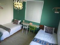 a bedroom with two beds and a table and a chandelier at Home in Hengchun Homestay in Hengchun South Gate