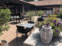 un patio con tavoli, sedie e fiori di Ruime luxe 4 persoons Chalet midden op de Veluwe a Hoenderloo