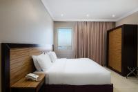 Un dormitorio con una cama blanca y un teléfono en un escritorio. en Mirada Purple Obhur - Serviced Apartments, en Yeda