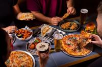 a group of people sitting around a table eating pizza at LyLo Auckland Hotel in Auckland