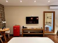a living room with a television and a red refrigerator at Barra do Piuva Porto Hotel in Ilhabela