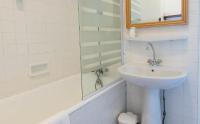 a white bathroom with a sink and a mirror at Hotel Le Chamois in L&#39;Alpe-d&#39;Huez