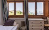 a bedroom with three windows and a bed and a dresser at Hotel Le Chamois in L&#39;Alpe-d&#39;Huez