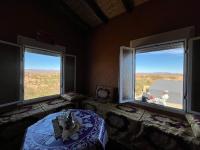 a room with two windows with a table and a person looking out at Auberge camping café restaurant Relax Tazoulait in Bou Dib