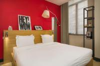 a bedroom with a white bed with a red wall at Maison Nô - Hôtel et Rooftop in Lyon