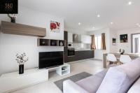 a white living room with a couch and a tv at Spacious, beautiful central penthouse with BBQ by 360 Estates in Tal-Pietà