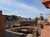 a stone bridge over a road next to a body of water at 5COMA2 Appartement proche plage in Collioure