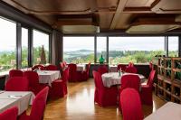 a restaurant with tables and red chairs and large windows at Landhotel Gottinger in Waldkirchen
