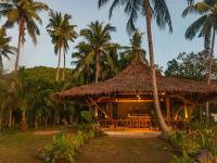 a resort with a straw hut with palm trees at Eco Sanctuaries Nature Lodge Nacpan Beach, El Nido in El Nido