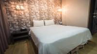 a large white bed in a room with a brick wall at The Riverside Hotel Fashion in Kaohsiung