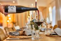 una persona vertiendo vino en una copa sobre una mesa en Weinforum Franken Hotel & Restaurant, en Eibelstadt